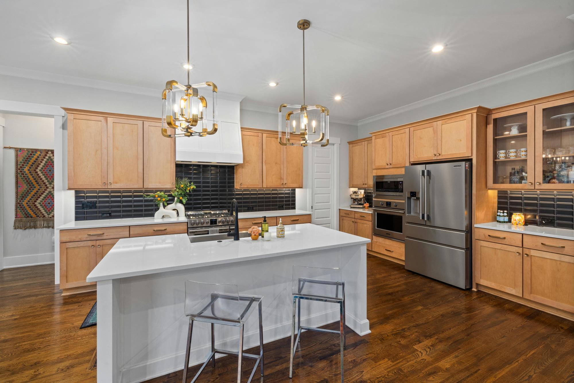 Modern kitchen with natural wood cabinetry, white island, and black tile backsplash by Managed Renovations in Chevy Chase, MD stock-optimized