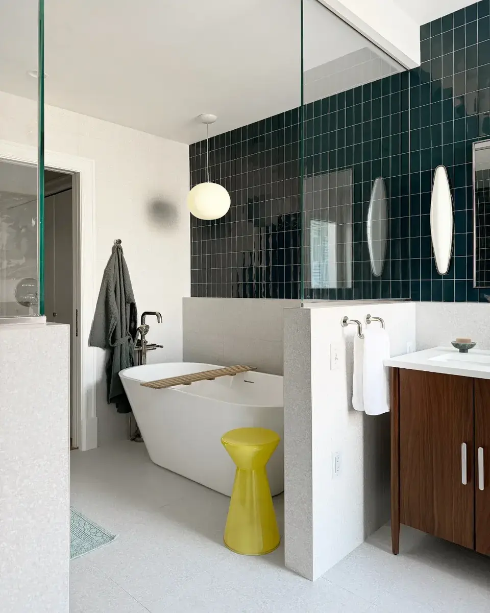 After photo of a complete primary bathroom renovation in NW Washington, DC showing a modern bathtub, glass shower enclosure, dark blue-green wall tile, and walnut vanity.
