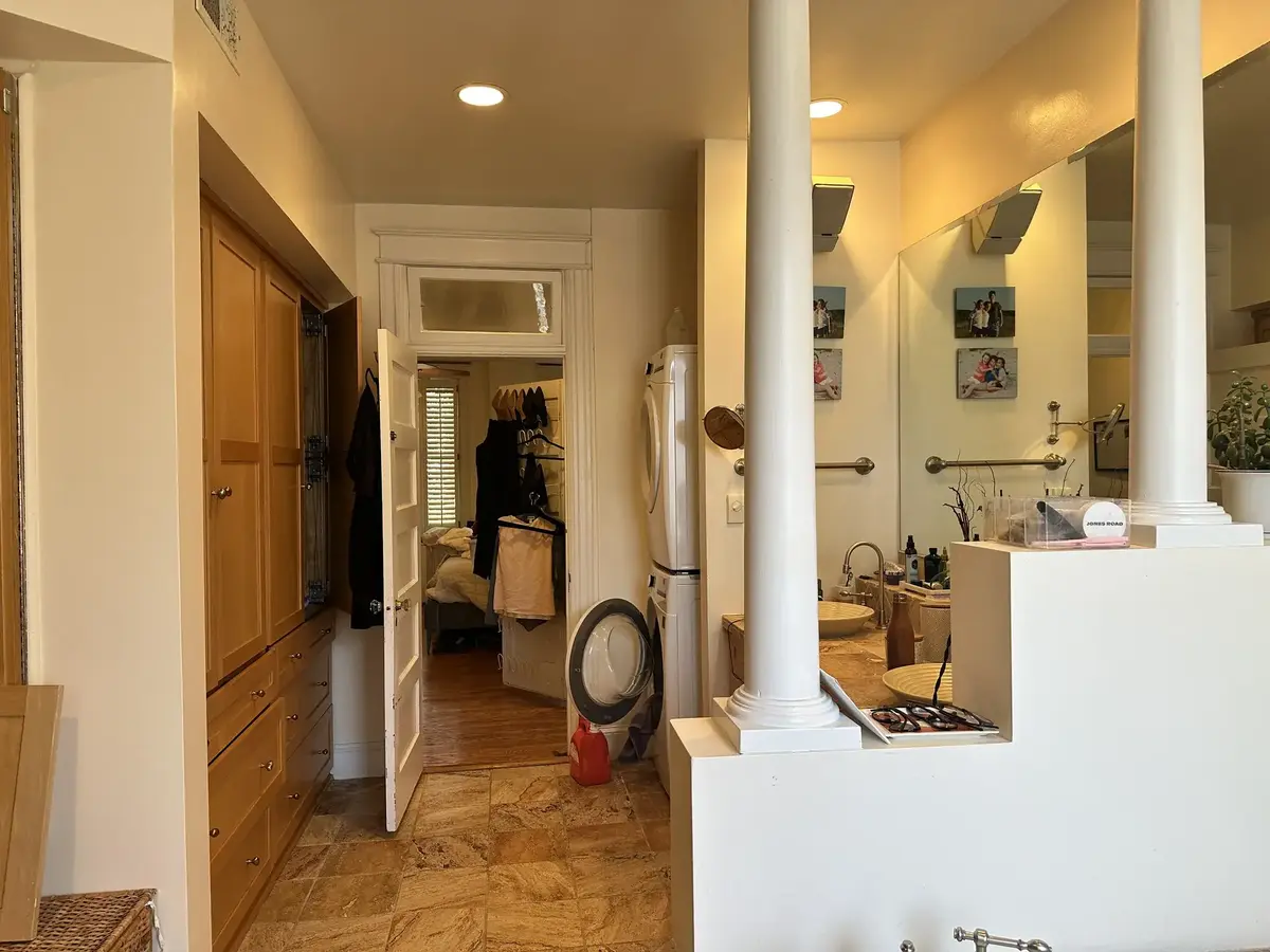 Before renovation view of the primary bathroom in NW Washington, DC showing the original wood cabinetry, partition walls, vanity, and tiled floor.