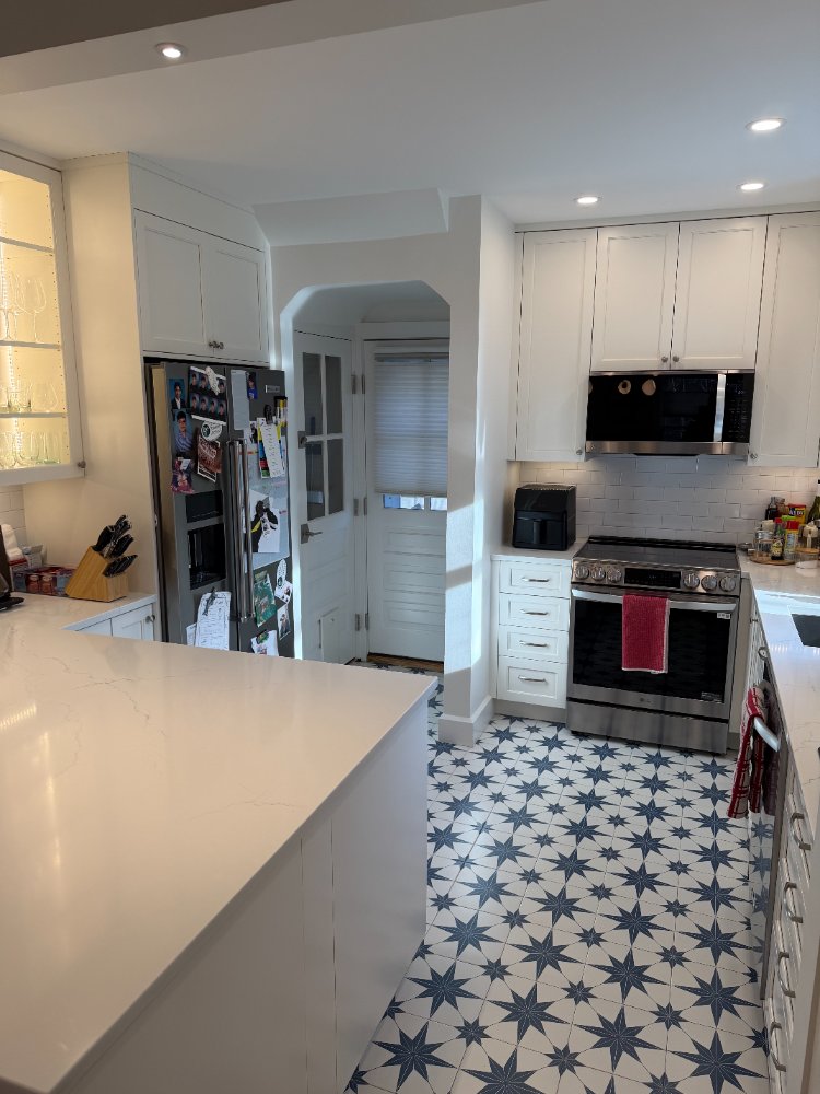 Kitchen remodel in Chevy Chase, MD featuring a quartz island with illuminated glass display cabinets.