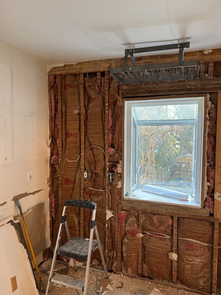 Demolition phase of the kitchen remodel in Chevy Chase, MD, exposing wall framing and insulation.