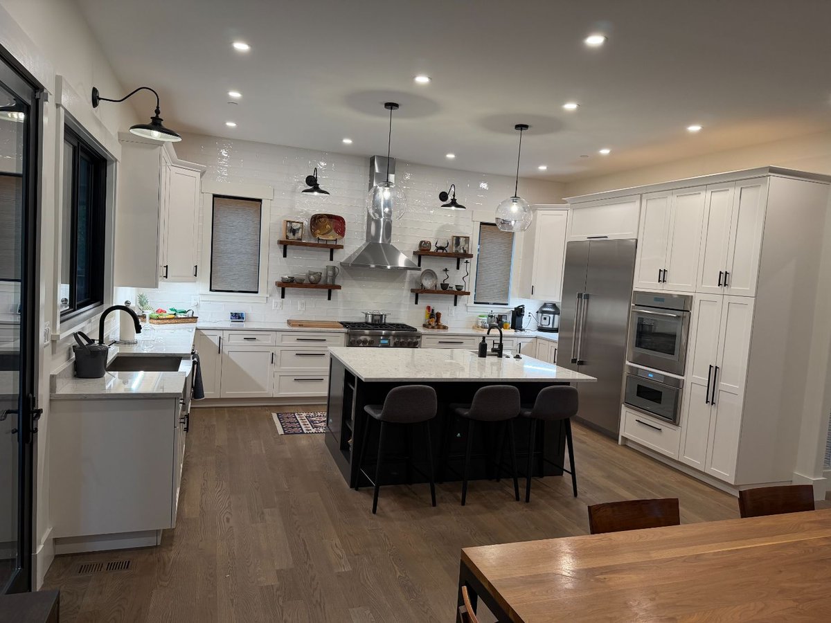Wide view of a custom kitchen in the new house in Chevy Chase, MD featuring white cabinetry and a large island.