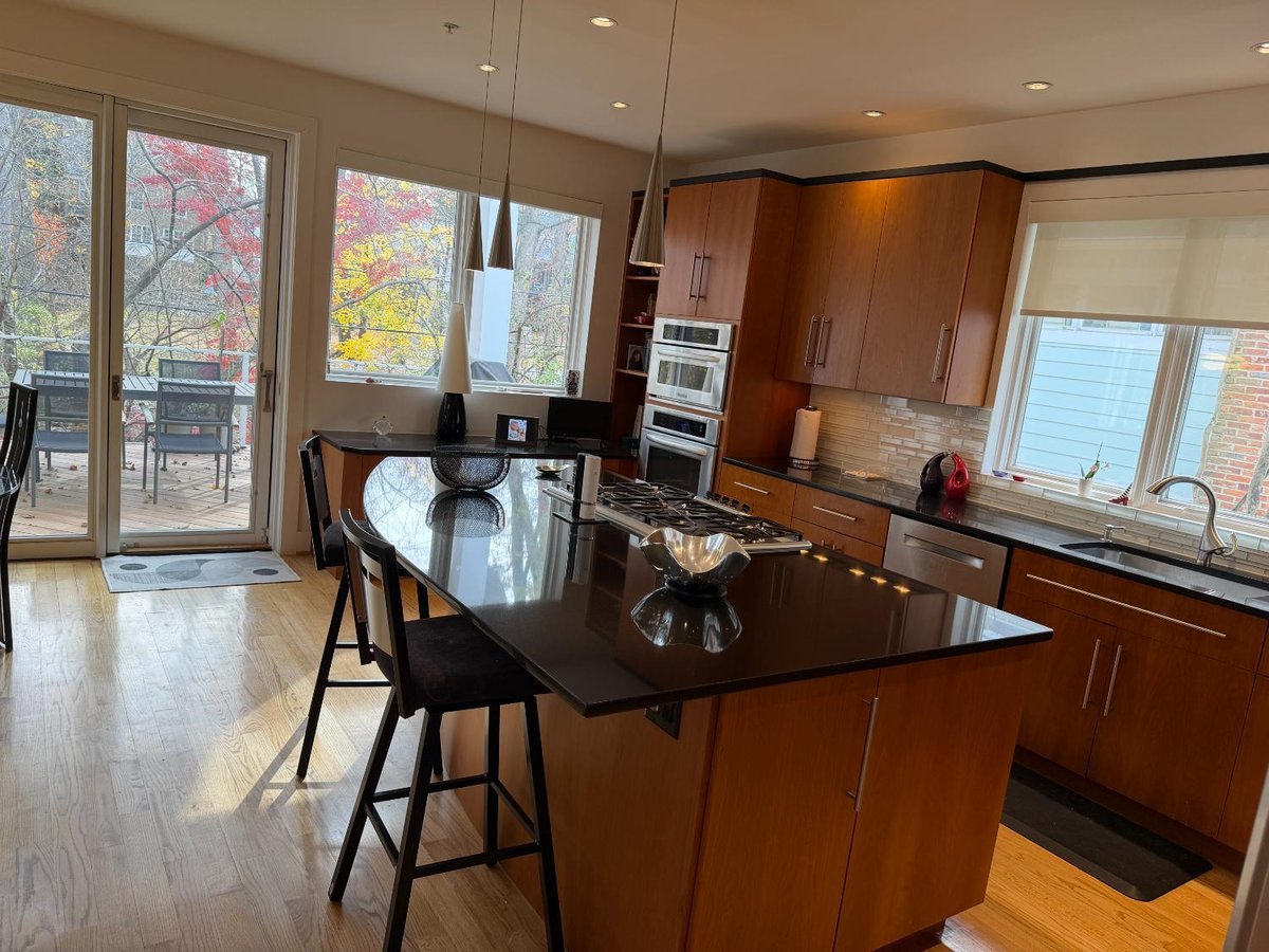 Bright custom kitchen in Chevy Chase, MD featuring a large black island and wood cabinetry.