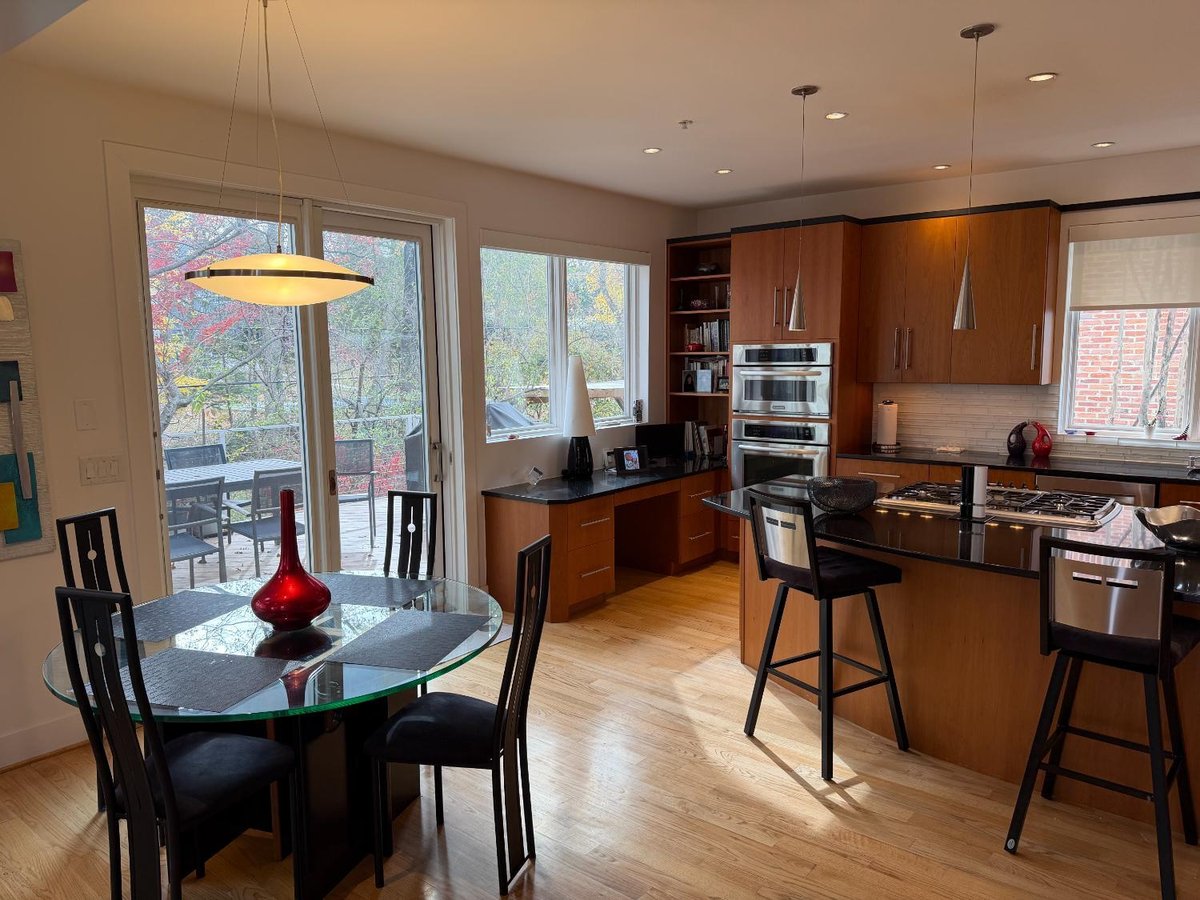 Contemporary new house kitchen in Chevy Chase, MD featuring a large black island and warm wood cabinetry.