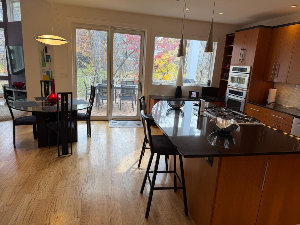 Open-concept new house kitchen in Chevy Chase, MD with a large island, dining area, and sliding glass doors.