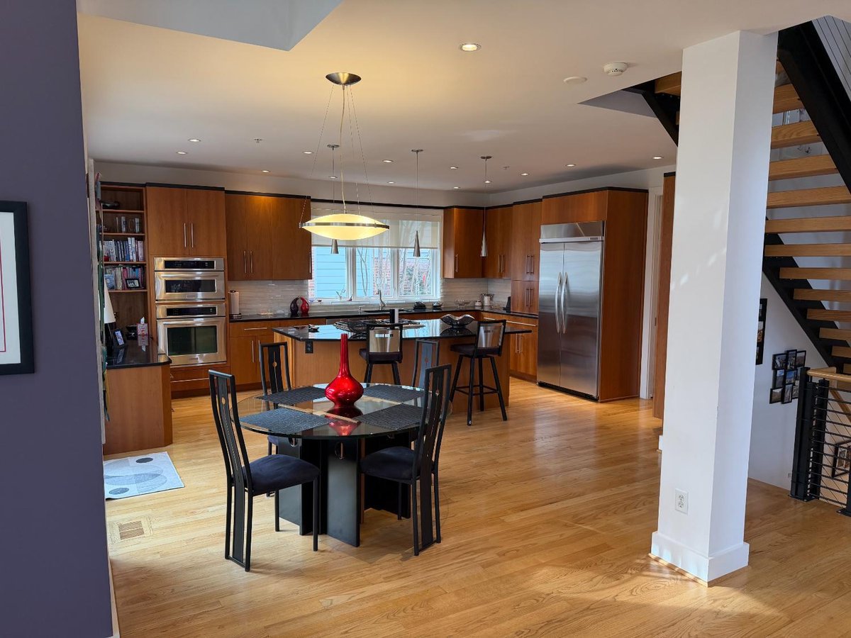 Spacious custom kitchen in Chevy Chase, MD with warm wood cabinetry, black countertops, and a central island.