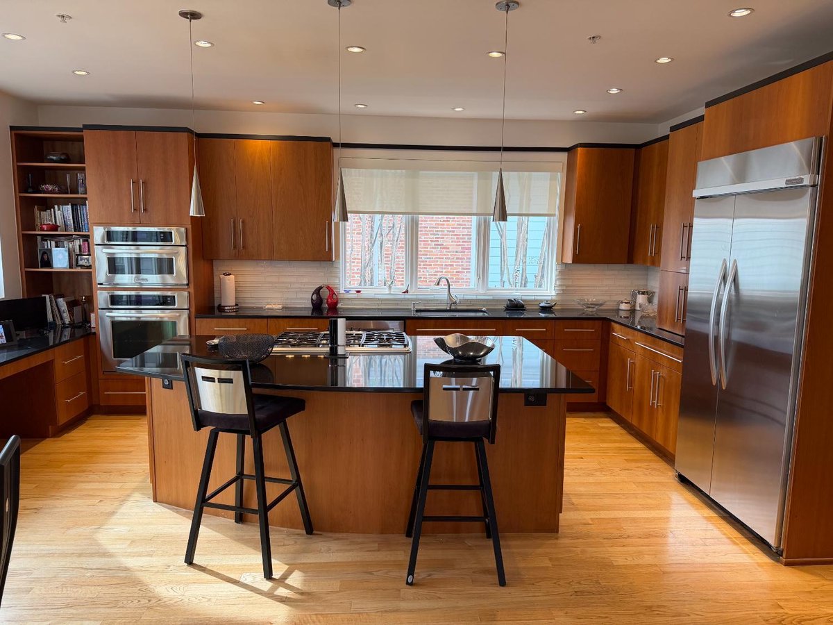 Spacious new house kitchen in Chevy Chase, MD with a large center island, custom wood cabinetry, and stainless steel appliances.