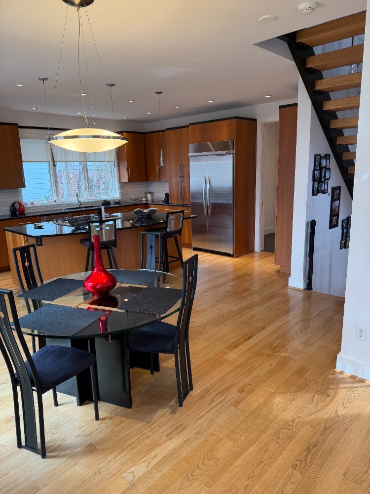 Wide view of the custom kitchen and dining area in Chevy Chase, MD with a central island and hardwood flooring.