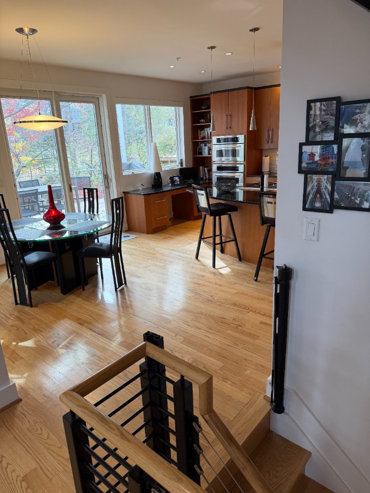 Wide view of the custom kitchen and dining area in Chevy Chase, MD with wood cabinetry and black countertops.