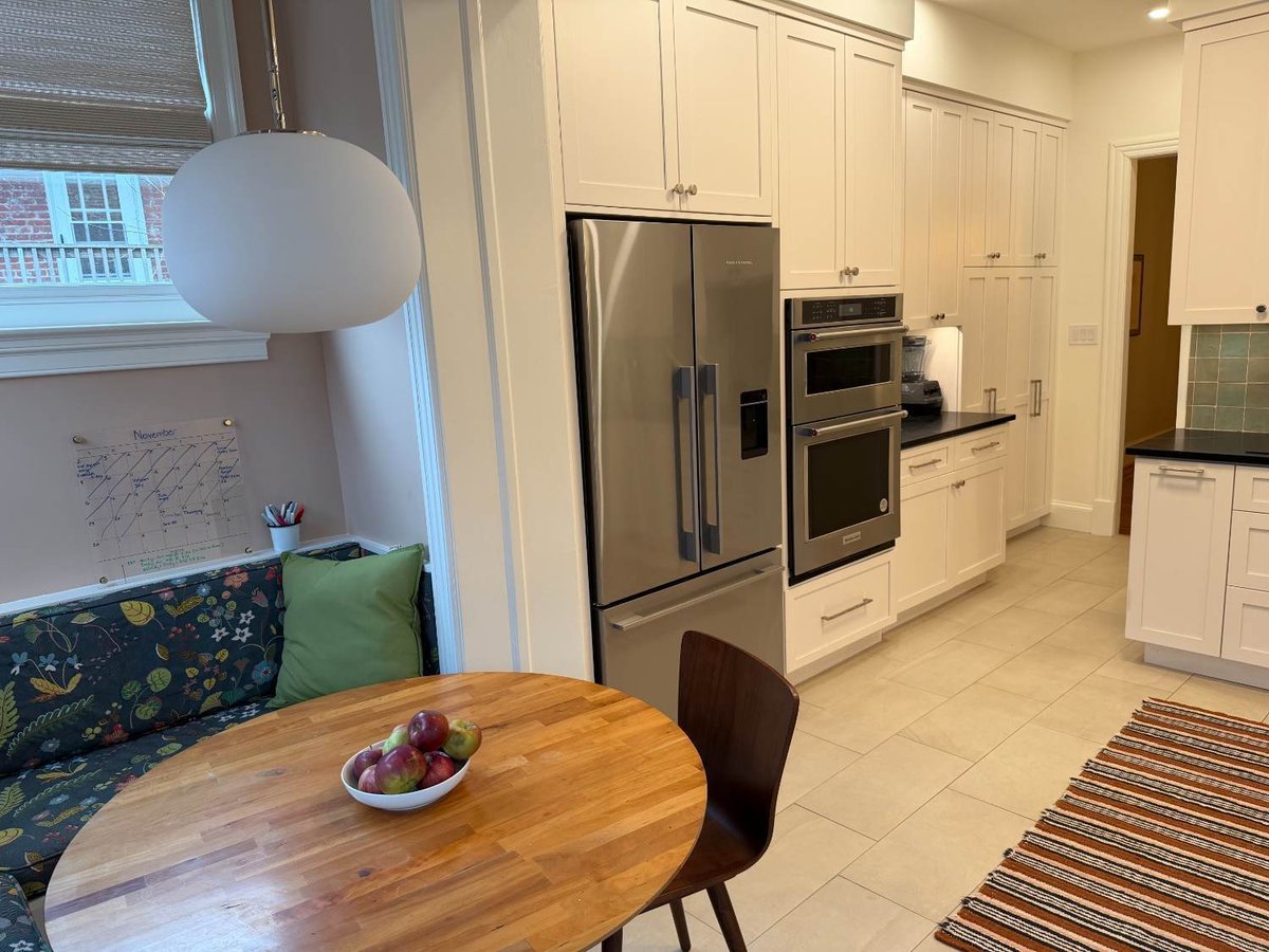 Breakfast nook and custom kitchen remodel featuring white shaker cabinetry, built-in appliances, and a dining area.
