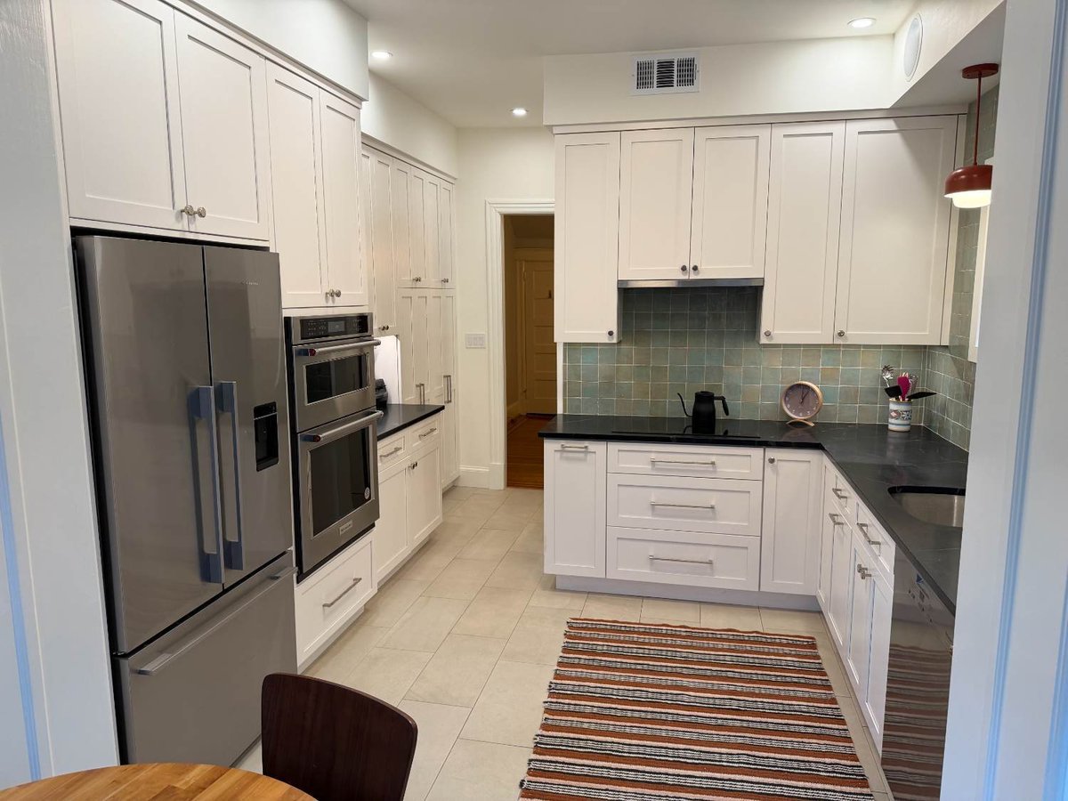 Custom kitchen remodel with white shaker cabinetry, green tile backsplash, and black countertops in NW DC