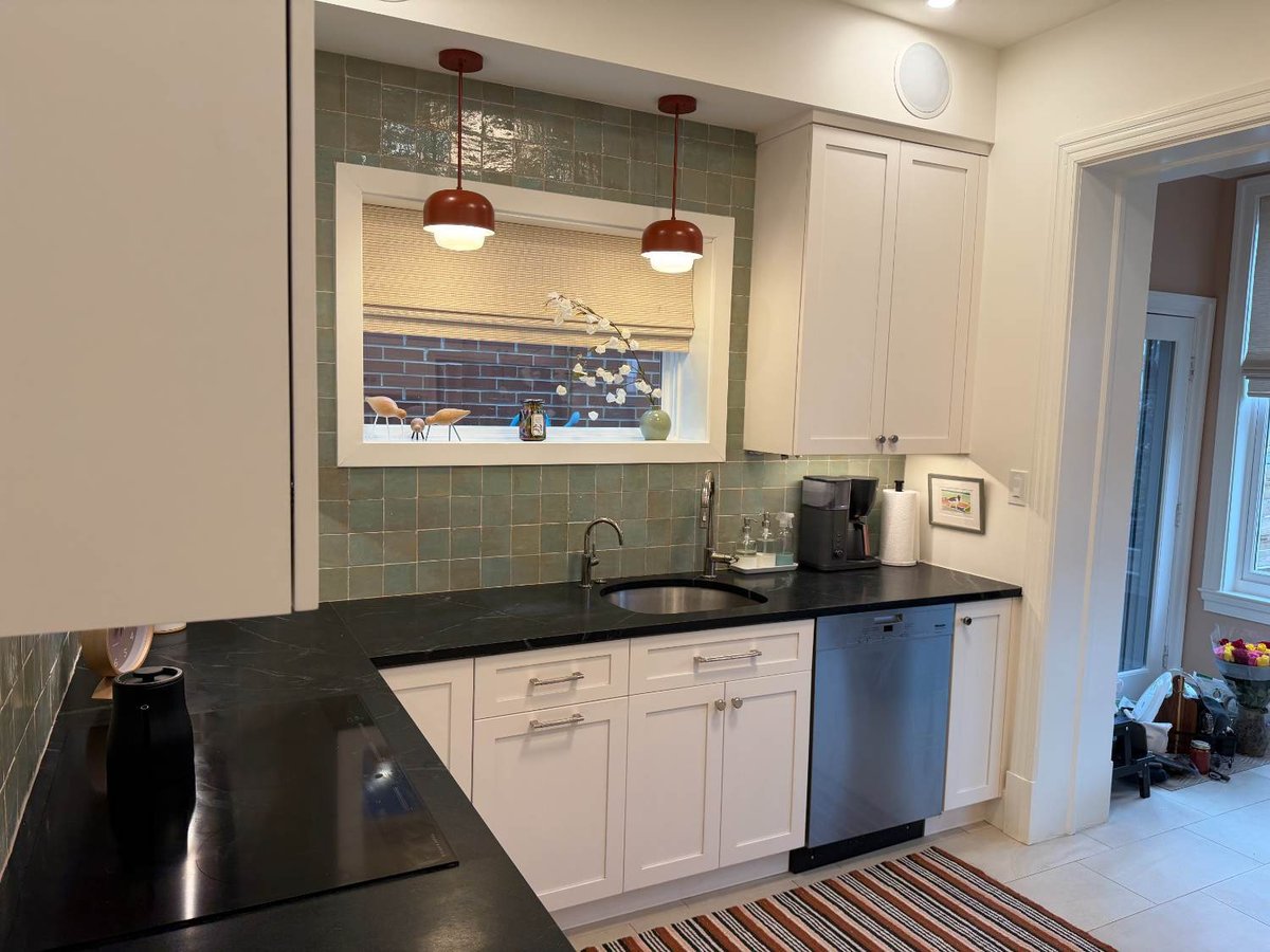 Kitchen sink wall remodeled with white shaker cabinets, green tile backsplash, and black countertops in Northwest Washington, D.C.