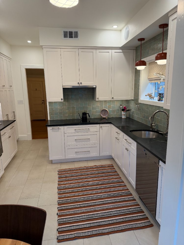 Remodeled kitchen featuring white shaker cabinets, black countertops, and a green tile backsplash in Northwest Washington, D.C.