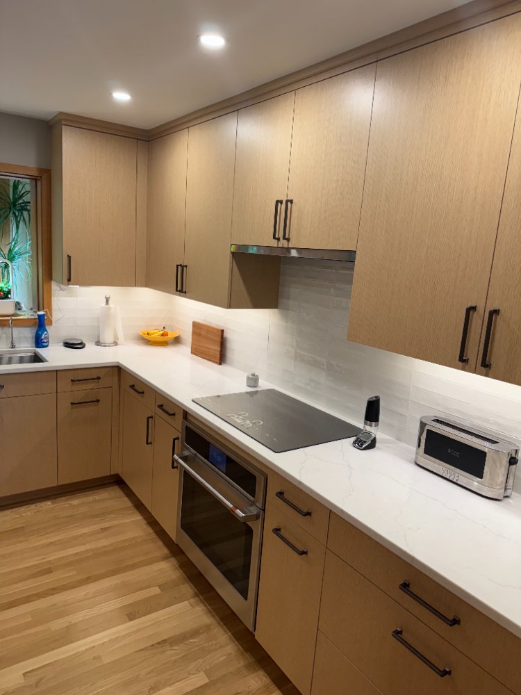 After view of the remodeled kitchen with custom cabinetry, quartz countertops, and under-cabinet lighting.