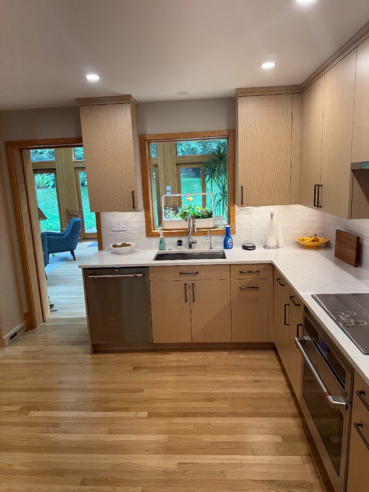 Bright kitchen remodel with custom light wood cabinets, quartz counters, and stainless steel appliances.