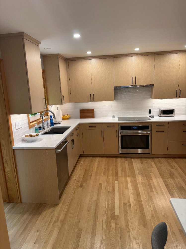 Wide view of the kitchen remodel featuring custom cabinetry, quartz countertops, and stainless steel appliances.