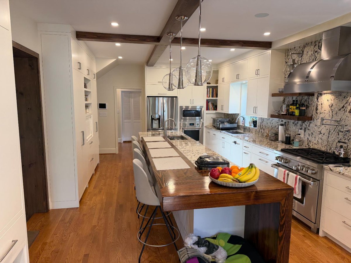 Completed custom kitchen in Northwest Washington, D.C. featuring a large island, white cabinetry, and exposed wood beams.