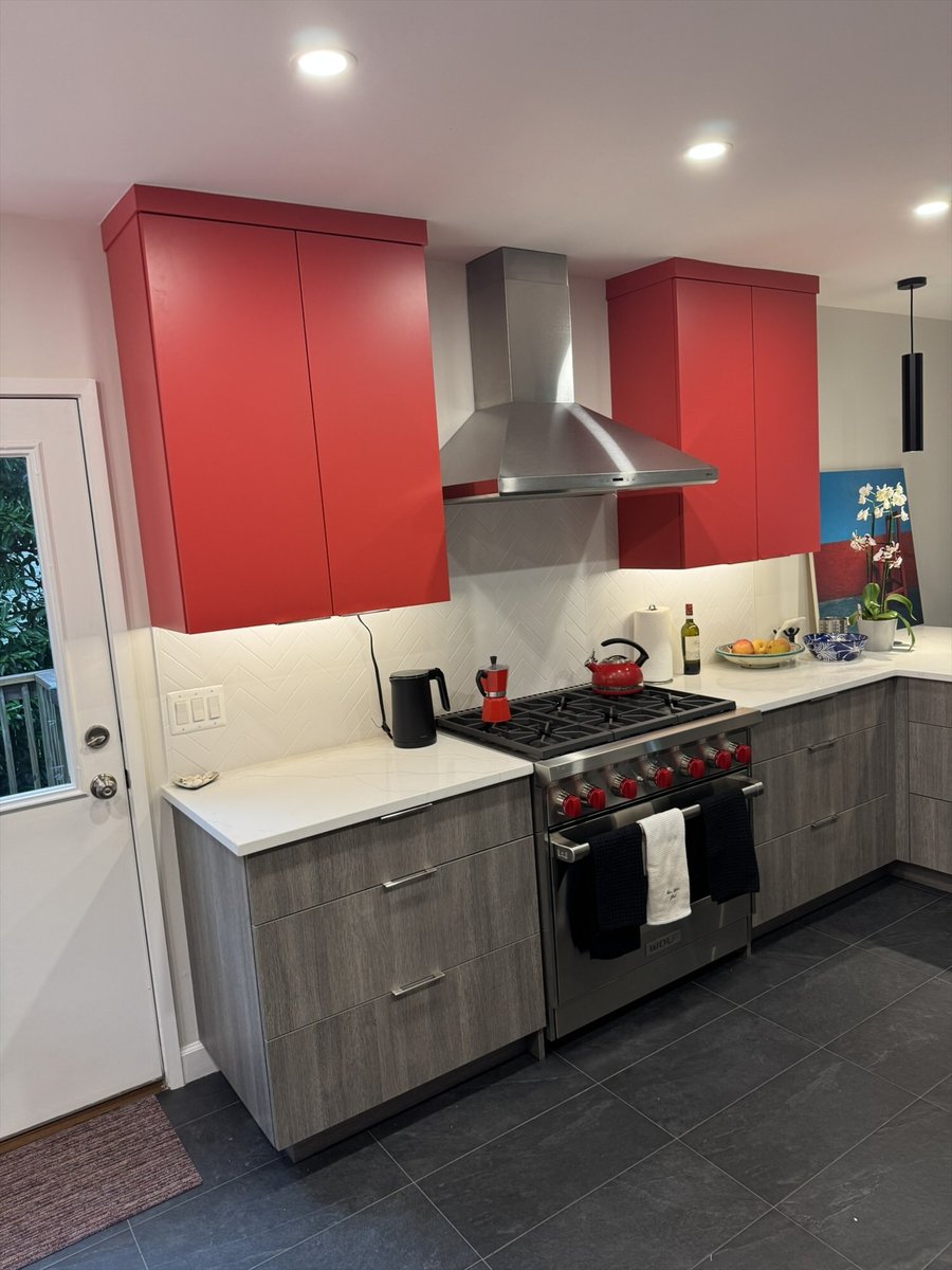 Contemporary kitchen with a Wolf gas range, stainless steel hood, red upper cabinets, and gray lower cabinets in Chevy Chase, MD