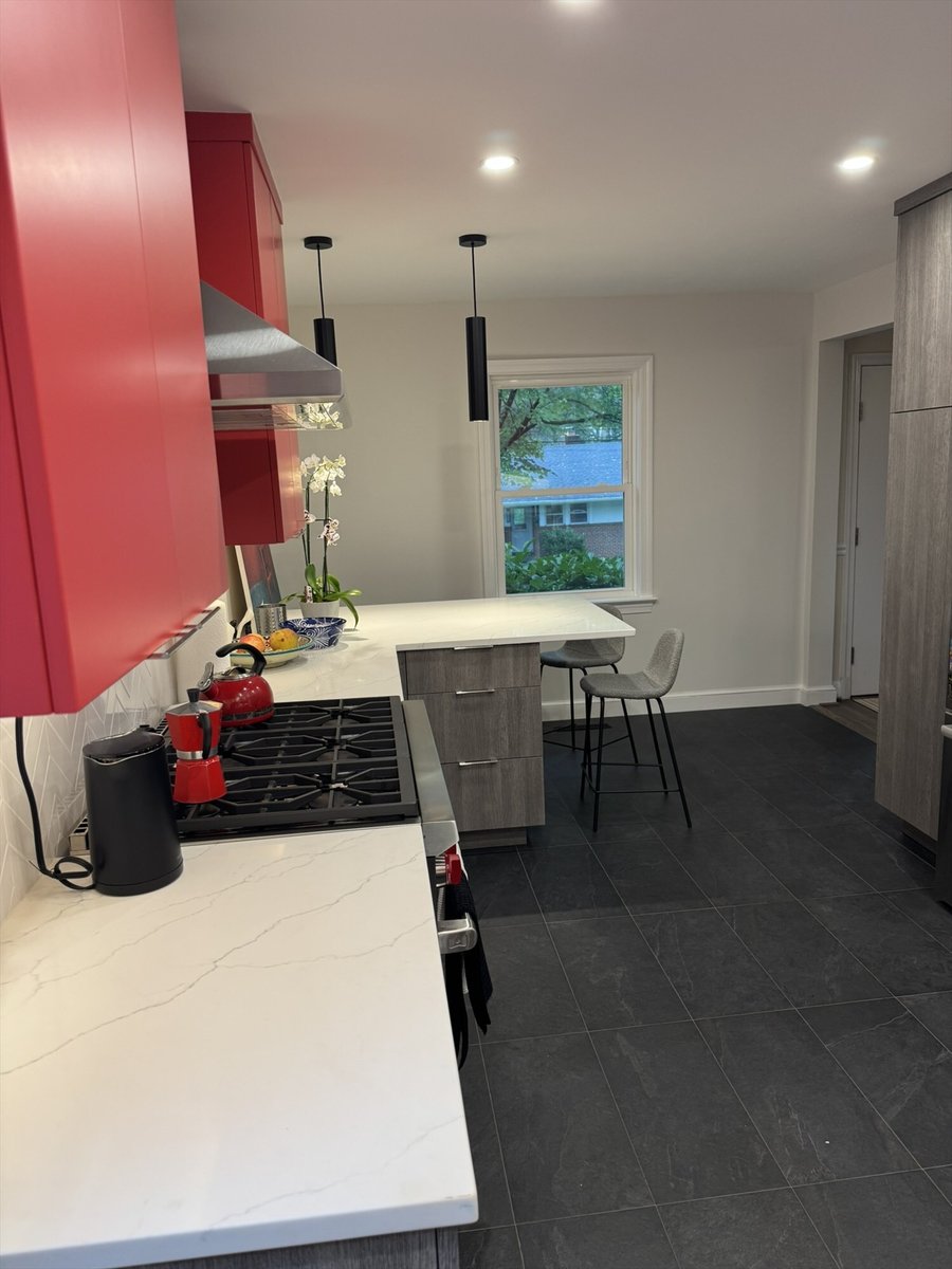 Modern kitchen remodel with a gas cooktop peninsula, red cabinetry, and a breakfast bar with seating in Chevy Chase, MD - optimi