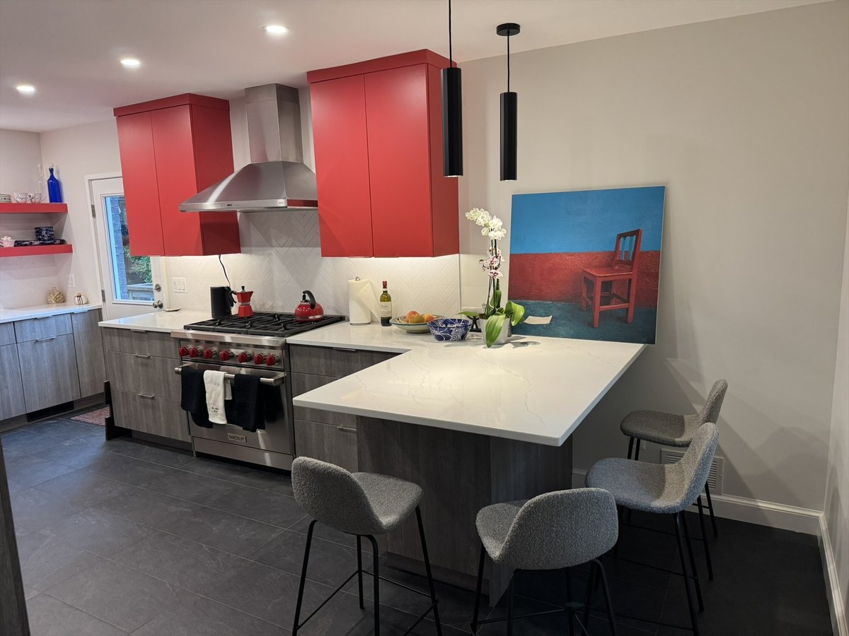 Modern kitchen remodel with red upper cabinets, gray lower cabinets, and a white quartz waterfall peninsula with seating in Chev
