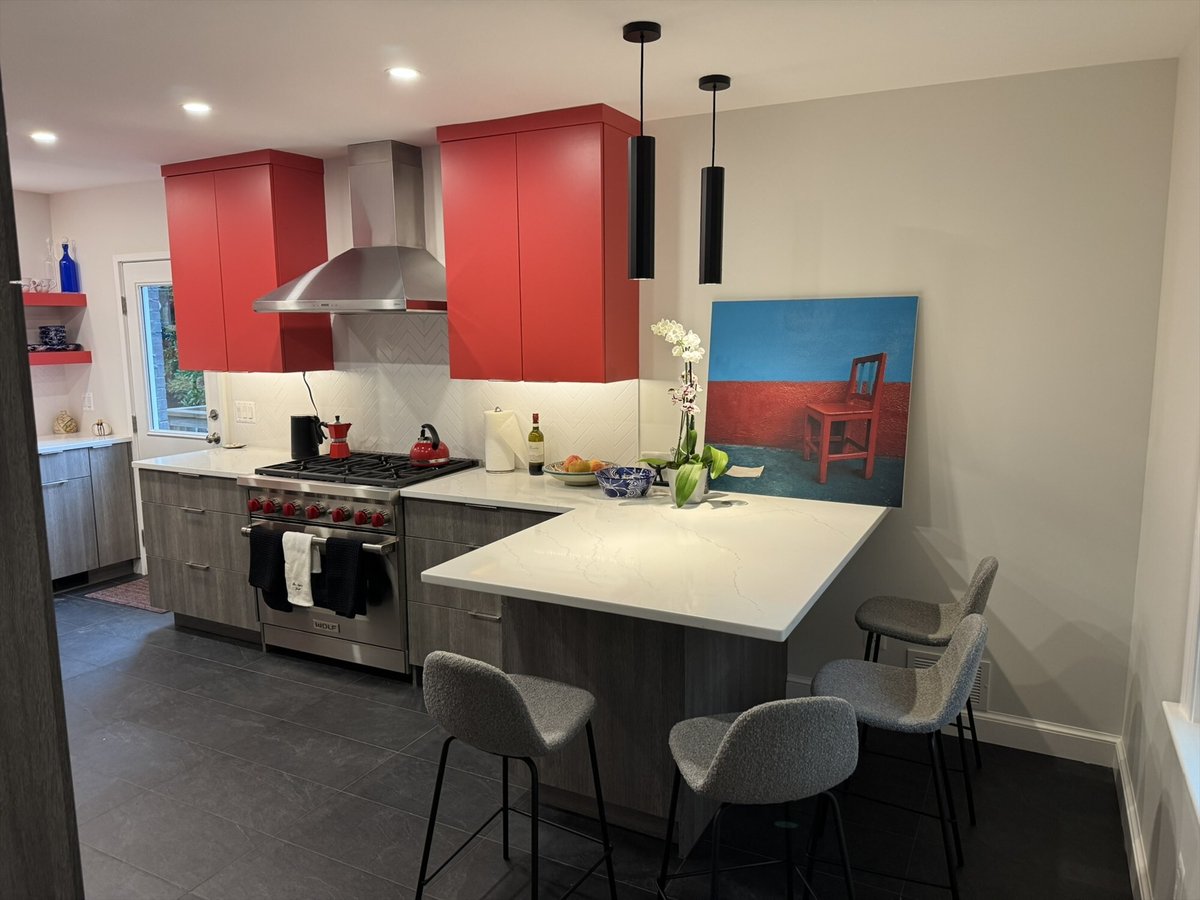 Modern kitchen with a Wolf gas range, stainless steel hood, and a white quartz waterfall peninsula in Chevy Chase, MD - optimize
