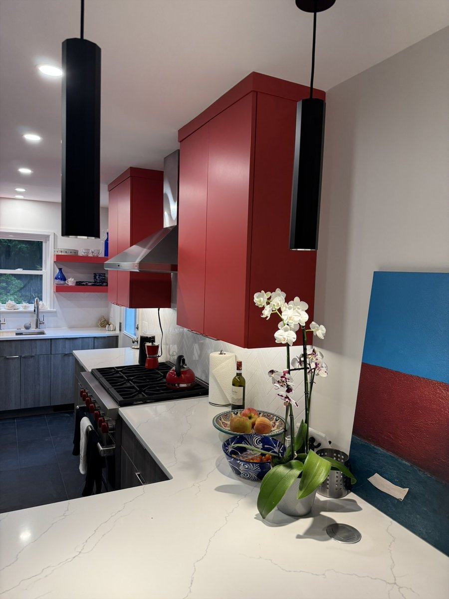 Modern kitchen with a gas cooktop, stainless steel hood, red cabinetry, and white quartz countertops in Chevy Chase, MD - optimi