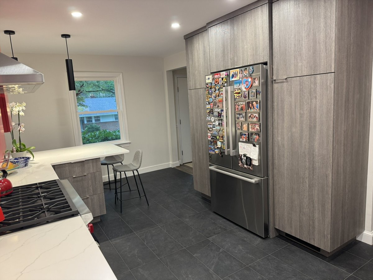 Remodeled kitchen with a breakfast bar, tall gray cabinetry, and a stainless steel refrigerator in Chevy Chase, MD - optimized