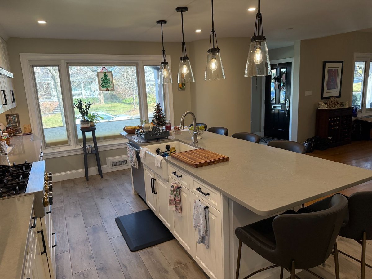 Kitchen remodel in Bethesda, MD with a large quartz island, farmhouse sink, and white shaker cabinets.