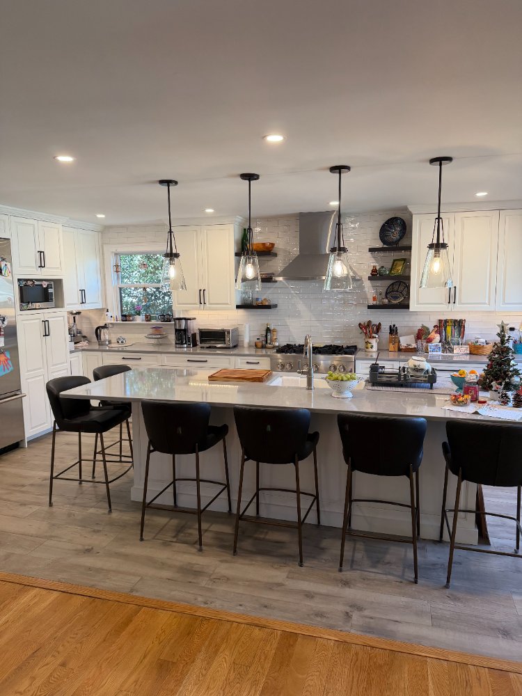 Modern kitchen remodel featuring a large quartz island, pendant lighting, and custom white cabinetry.