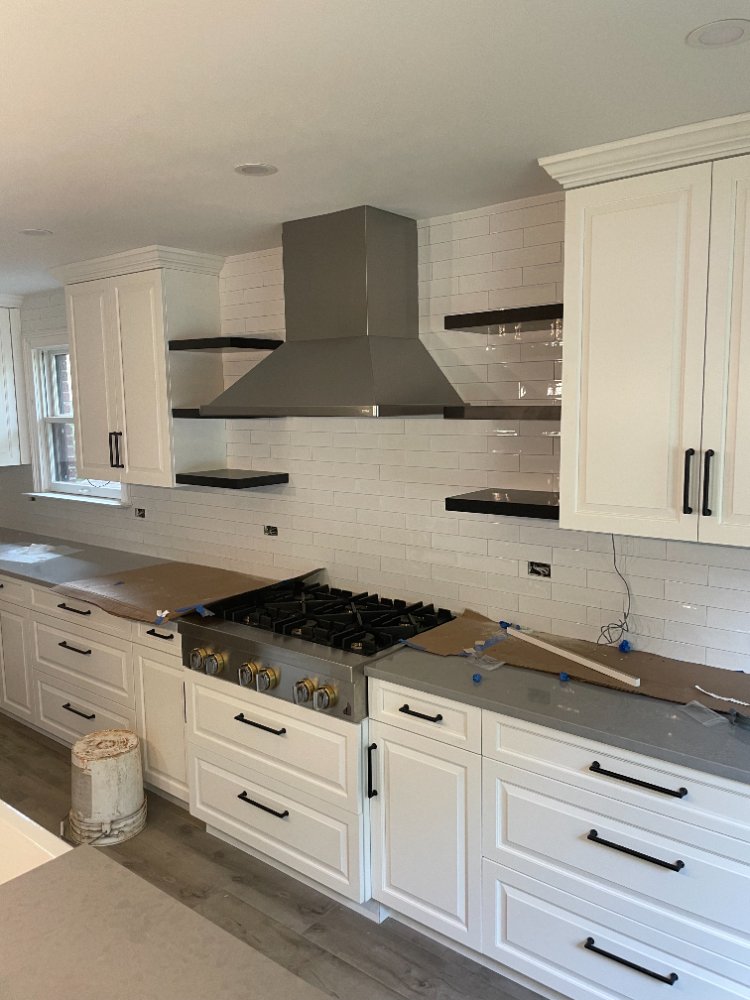 Modern kitchen remodel with white shaker cabinets, stainless range hood, and subway tile in Bethesda, MD.