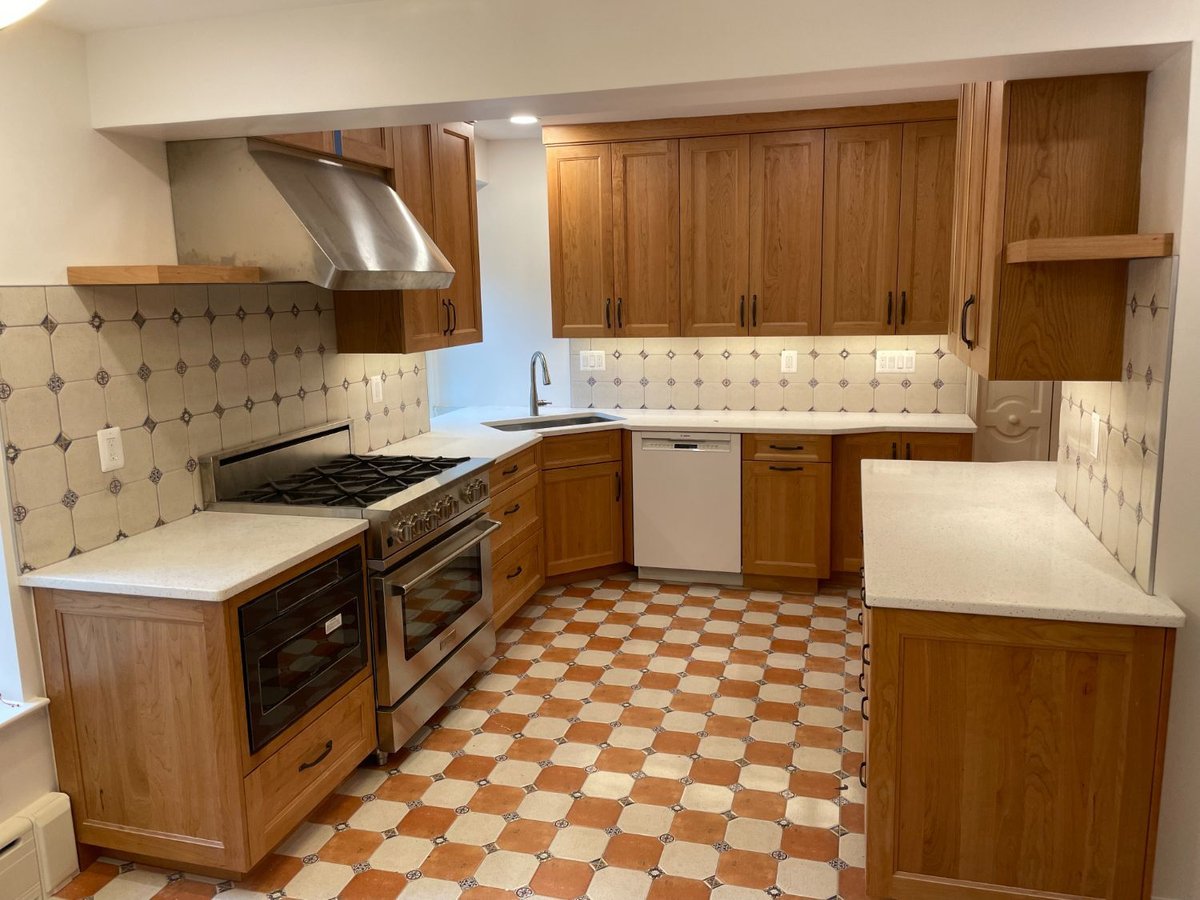 Finished kitchen remodel featuring custom wood cabinetry, quartz countertops, and decorative tile flooring.