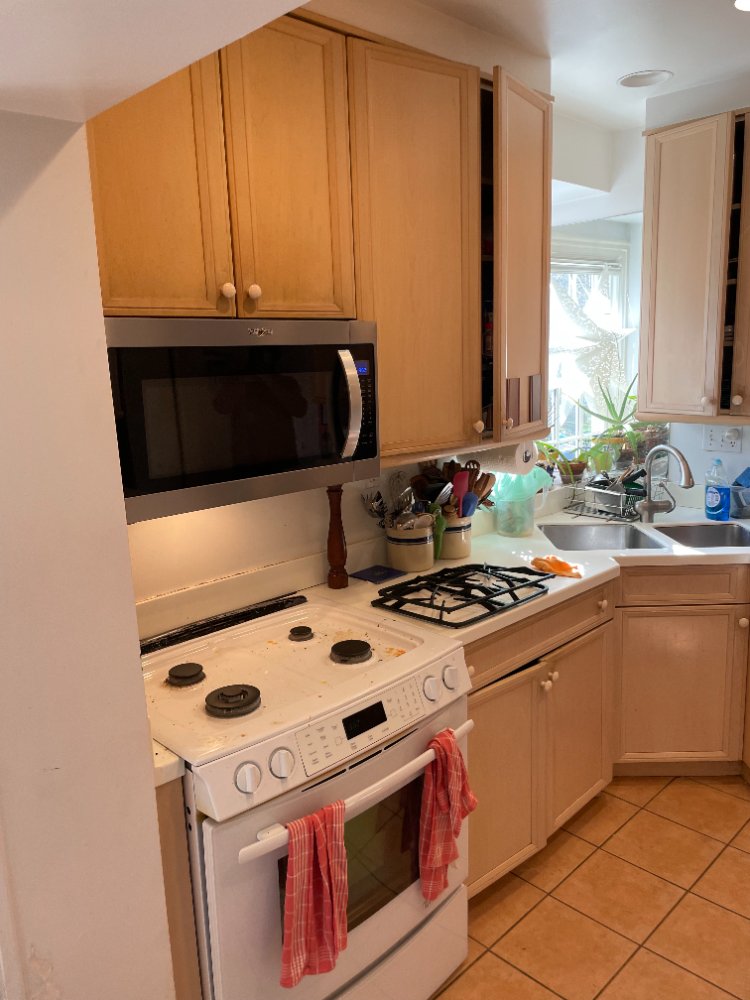 Pre-remodel kitchen in Chevy Chase, MD showcasing original wood cabinets, white countertops, and an electric range.