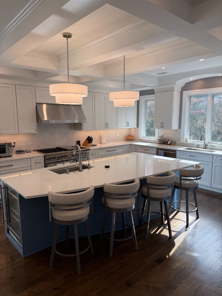 Bright kitchen renovation in Chevy Chase, MD with a blue island, white shaker cabinets, and stainless steel appliances.