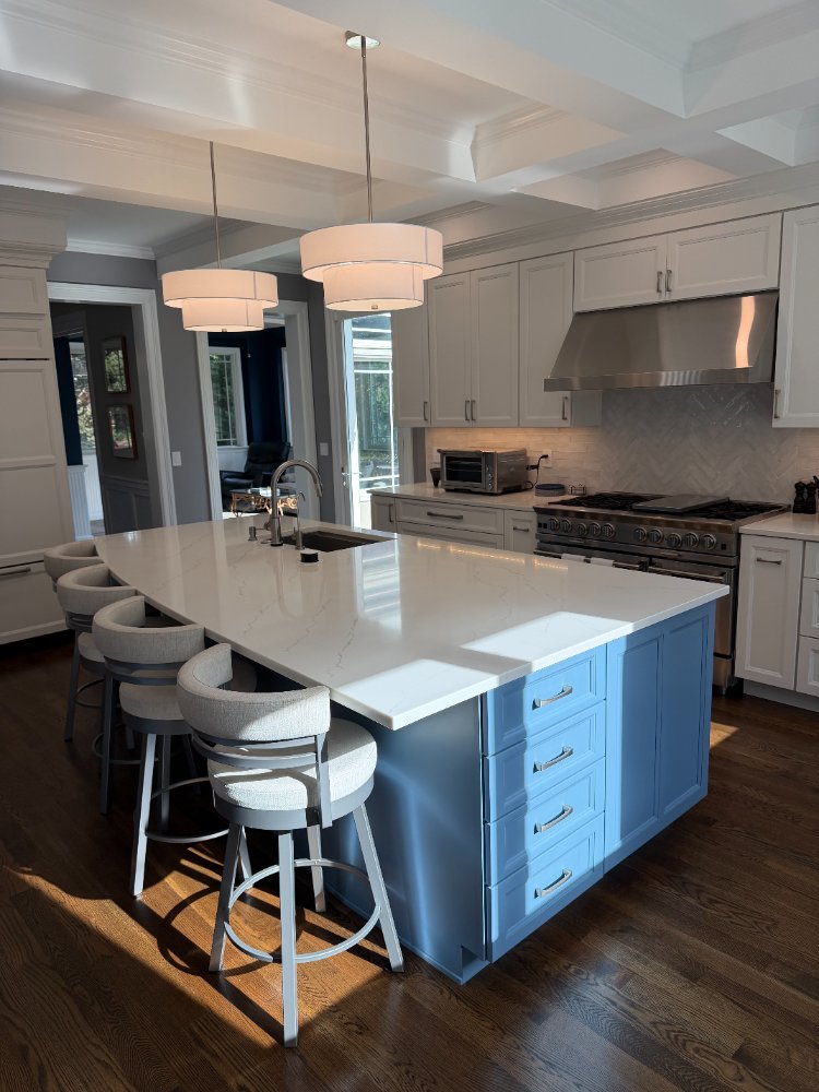 Remodeled kitchen featuring a blue quartz island, white cabinetry, and a stainless steel range in Chevy Chase, MD.