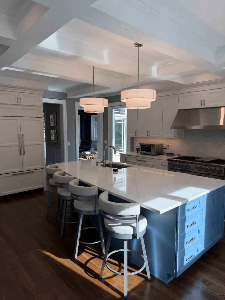 Remodeled kitchen featuring a blue waterfall island, custom bar seating, and white cabinetry in Chevy Chase, MD.
