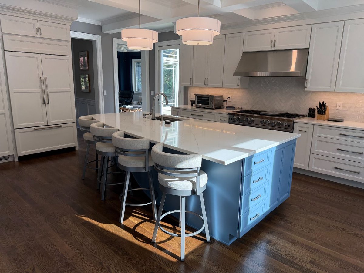 Remodeled kitchen featuring a blue waterfall island, white shaker cabinets, and a professional gas range in Chevy Chase, MD.