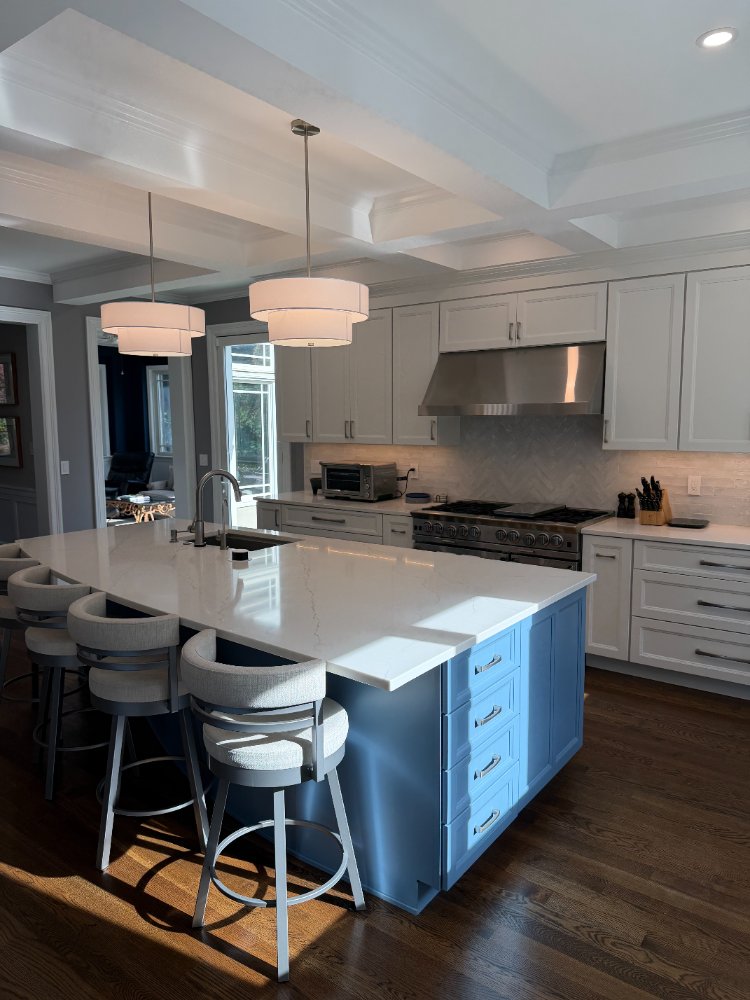 Remodeled kitchen highlighting a blue quartz island, coffered ceiling, and custom white cabinetry in Chevy Chase, MD.