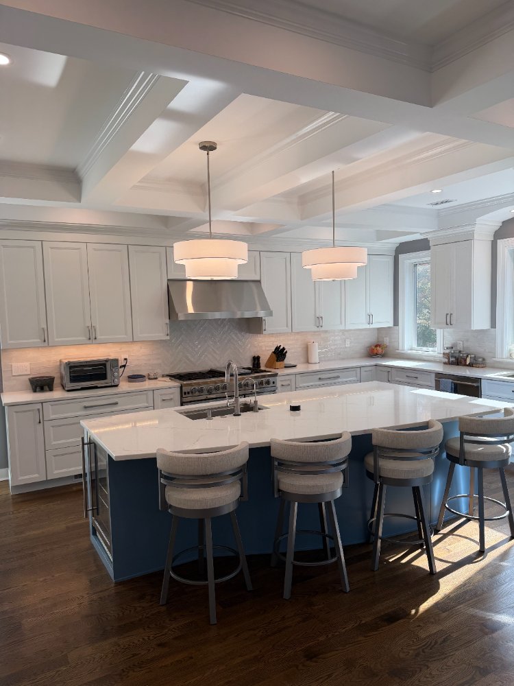Remodeled kitchen with a blue quartz island, white cabinetry, and oversized windows in Chevy Chase, MD.