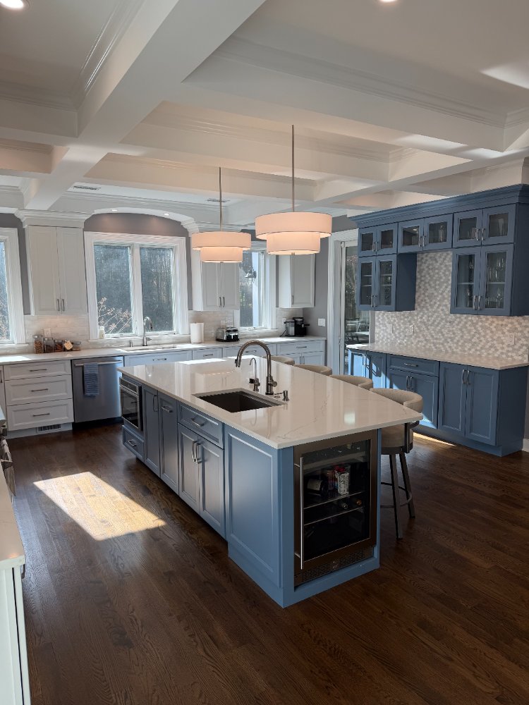 Remodeled kitchen featuring a blue island, custom white cabinetry, and pendant lighting in Chevy Chase, MD.