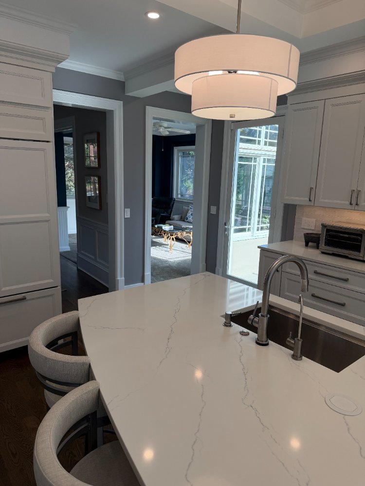 Remodeled kitchen with a quartz waterfall island, custom cabinetry, and pendant lighting in Chevy Chase, MD.