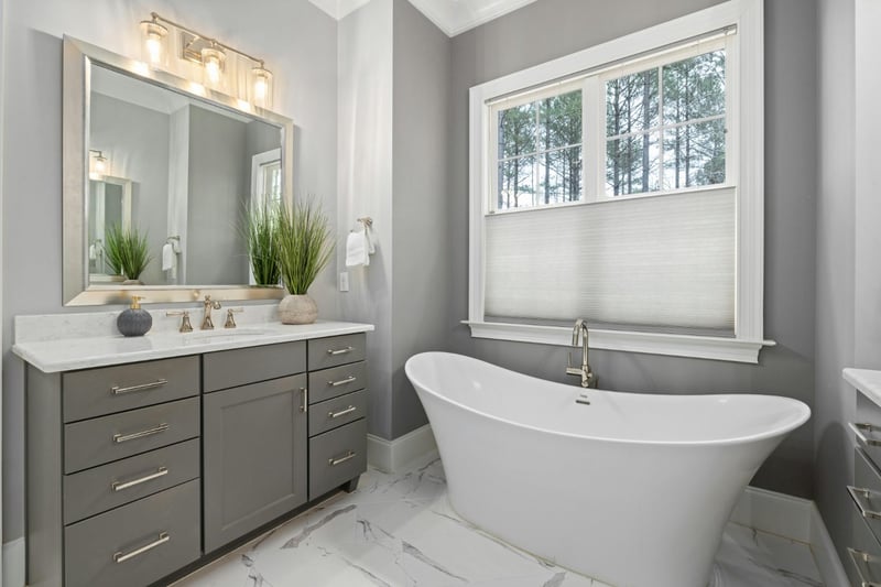 Luxury bathroom with gray vanity, freestanding soaking tub, and marble flooring in a bathroom addition by Managed Renovations in-optimized